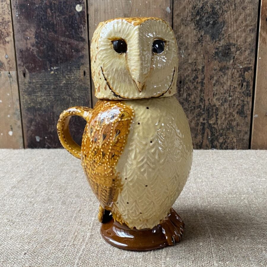 Carole Glover slipware glazed Owl Jug against a wooden background