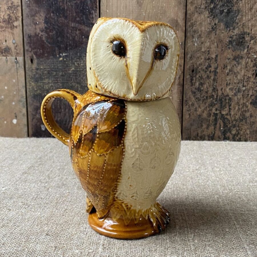 Carole Glover slipware glazed Owl Jug against a wooden background
