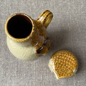 Carole Glover slipware glazed Owl Jug against a wooden background