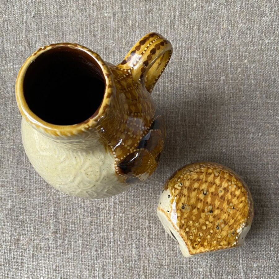 Carole Glover slipware glazed Owl Jug against a wooden background