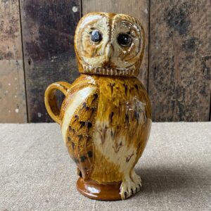 Carole Glover slipware glazed Owl Jug against a wooden background
