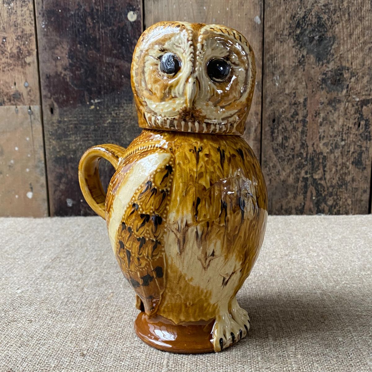 Carole Glover slipware glazed Owl Jug against a wooden background