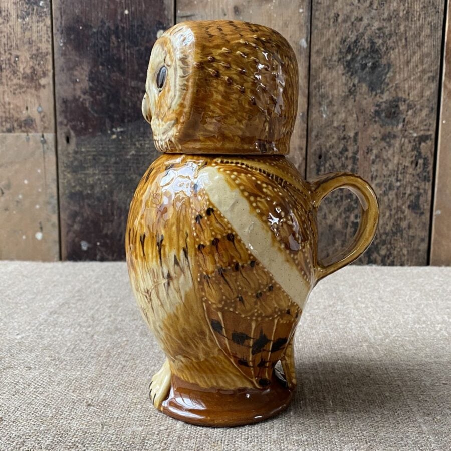 Carole Glover slipware glazed Owl Jug against a wooden background