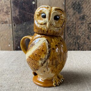 Carole Glover slipware glazed Owl Jug against a wooden background