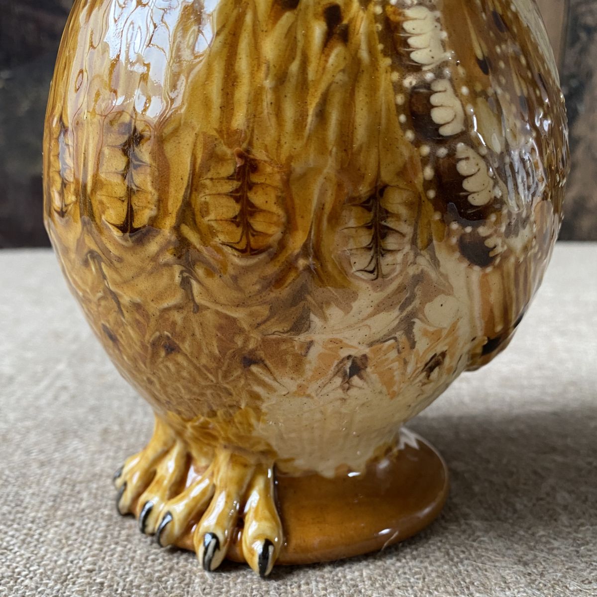 Carole Glover slipware glazed Owl Jug against a wooden background