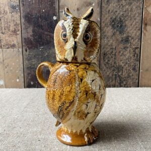 Carole Glover slipware glazed Owl Jug against a wooden background