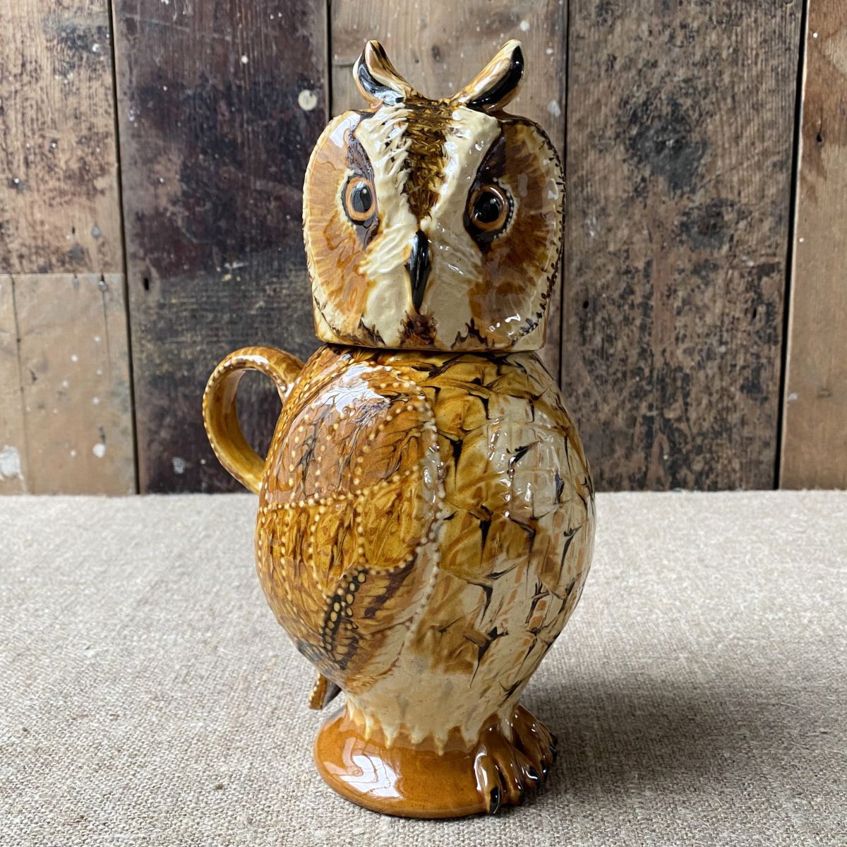 Carole Glover slipware glazed Owl Jug against a wooden background