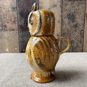 Carole Glover slipware glazed Owl Jug against a wooden background