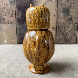 Carole Glover slipware glazed Owl Jug against a wooden background