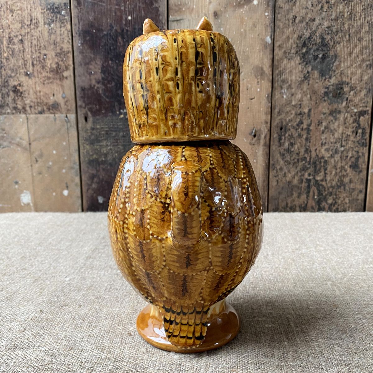 Carole Glover slipware glazed Owl Jug against a wooden background