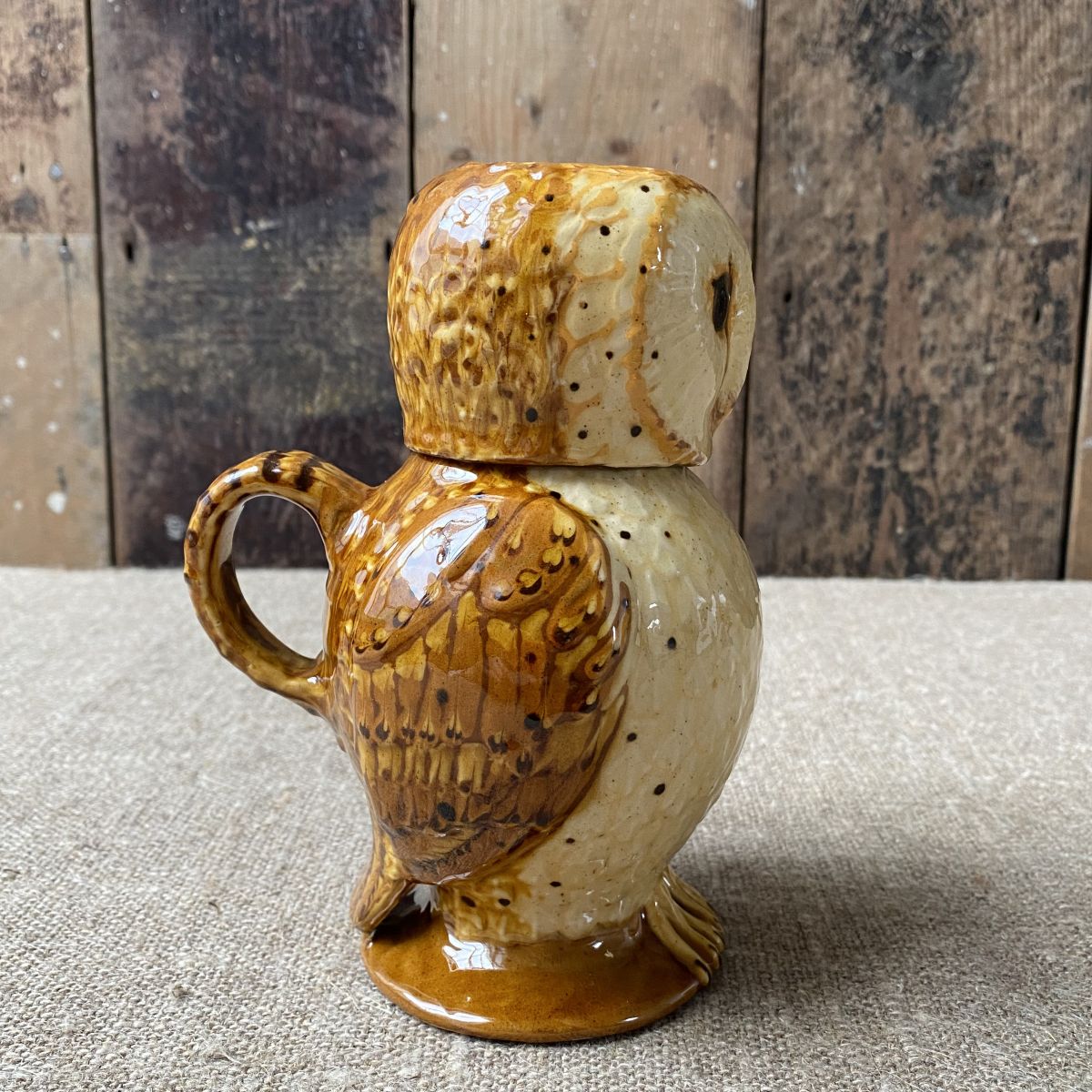 Carole Glover slipware glazed Owl Jug against a wooden background