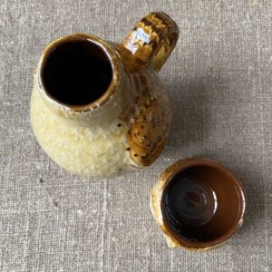 Carole Glover slipware glazed Owl Jug against a wooden background