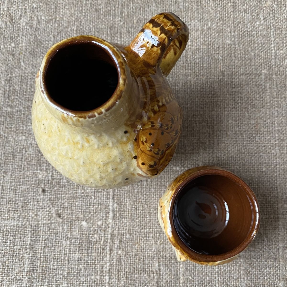 Carole Glover slipware glazed Owl Jug against a wooden background