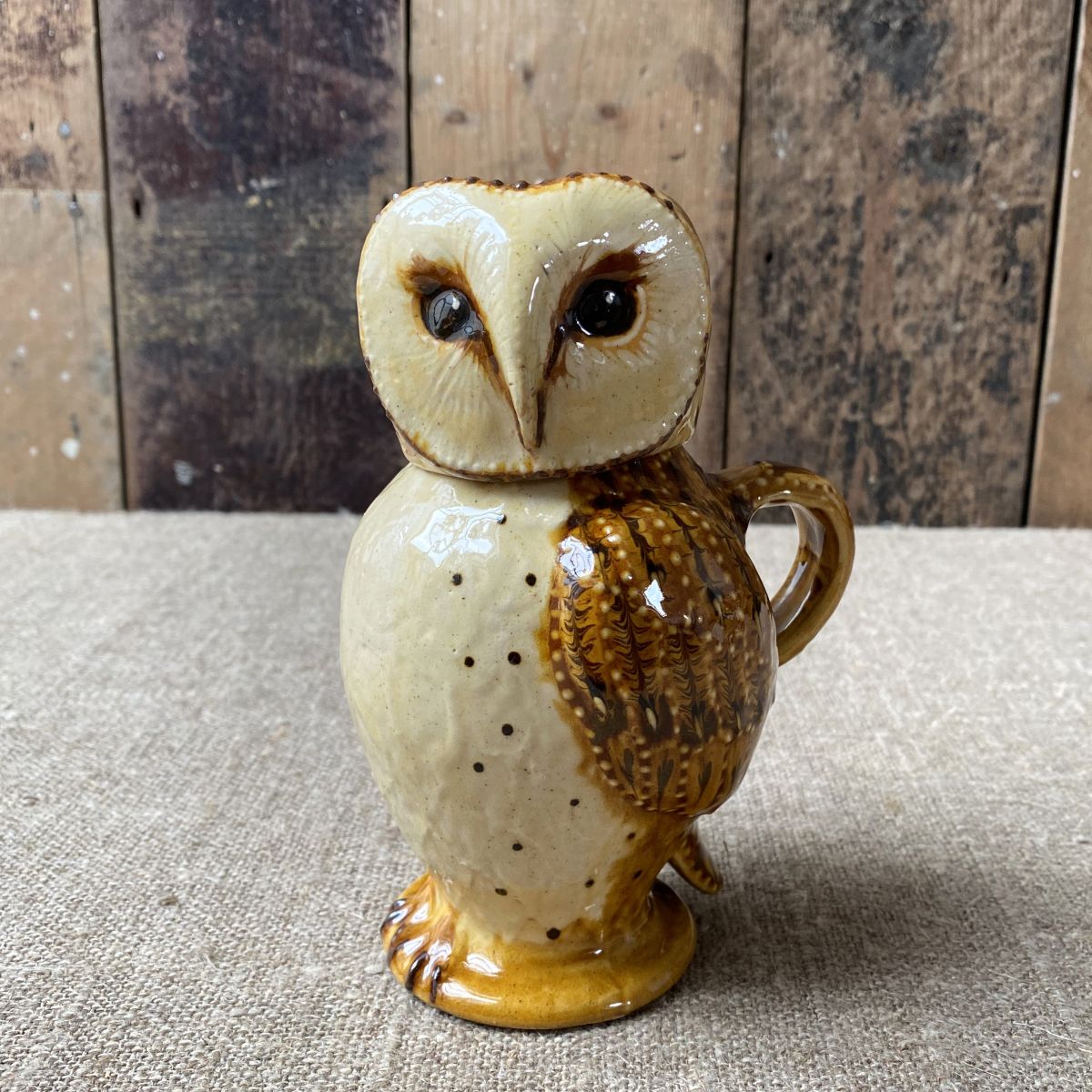 Carole Glover slipware glazed Owl Jug against a wooden background