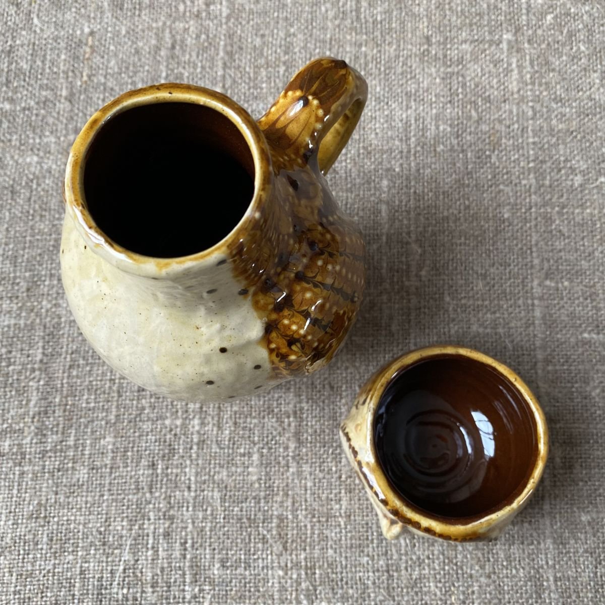 Carole Glover slipware glazed Owl Jug against a wooden background