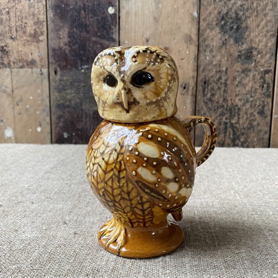 Carole Glover slipware glazed Owl Jug against a wooden background