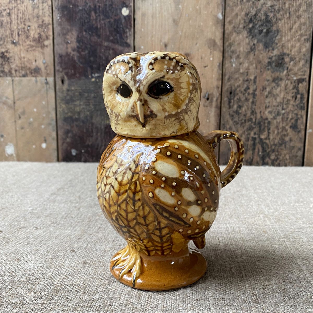 Carole Glover slipware glazed Owl Jug against a wooden background