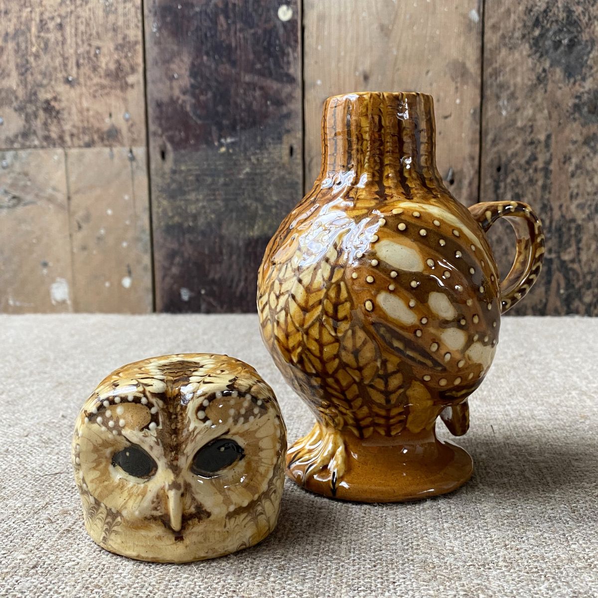 Carole Glover slipware glazed Owl Jug against a wooden background