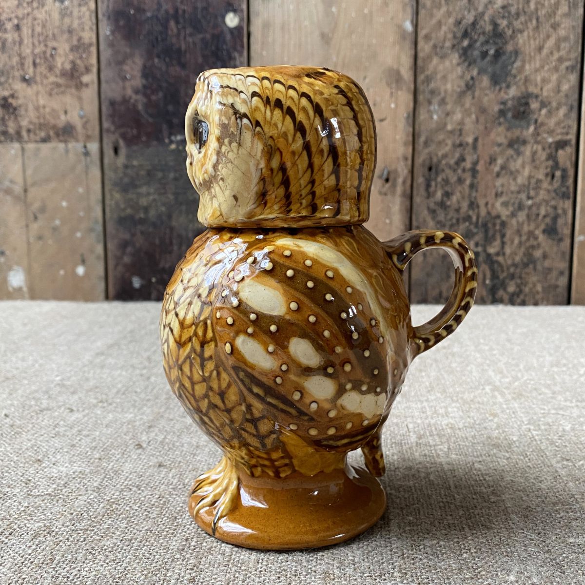 Carole Glover slipware glazed Owl Jug against a wooden background