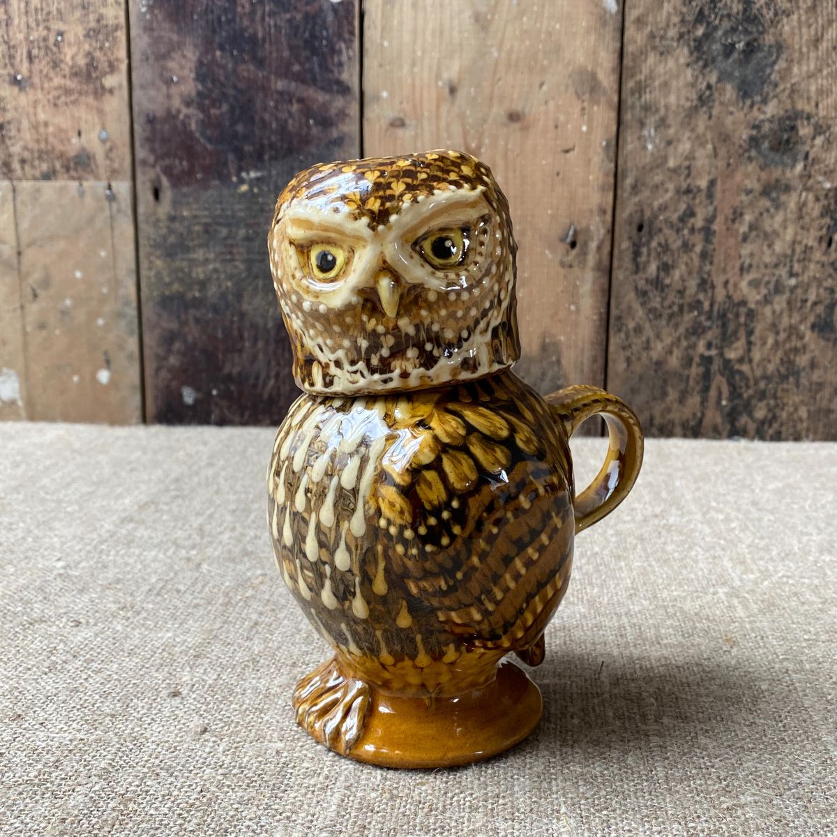 Carole Glover slipware glazed Owl Jug against a wooden background