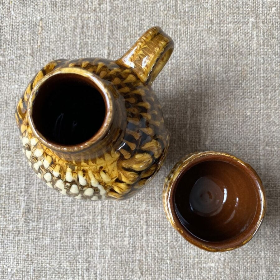Carole Glover slipware glazed Owl Jug against a wooden background