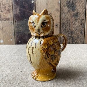 Carole Glover slipware glazed Owl Jug against a wooden background
