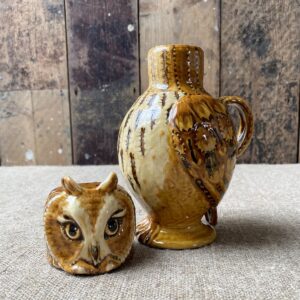 Carole Glover slipware glazed Owl Jug against a wooden background