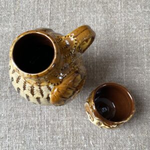 Carole Glover slipware glazed Owl Jug against a wooden background