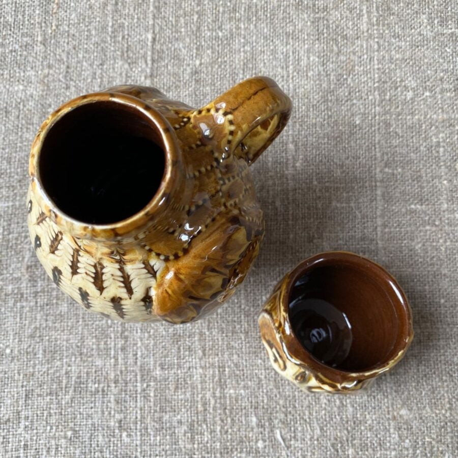 Carole Glover slipware glazed Owl Jug against a wooden background