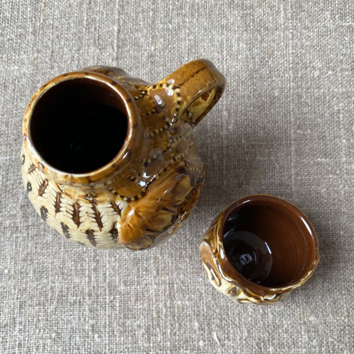 Carole Glover slipware glazed Owl Jug against a wooden background