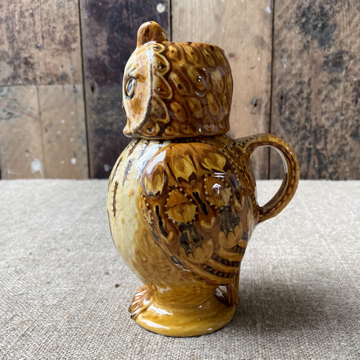 Carole Glover slipware glazed Owl Jug against a wooden background