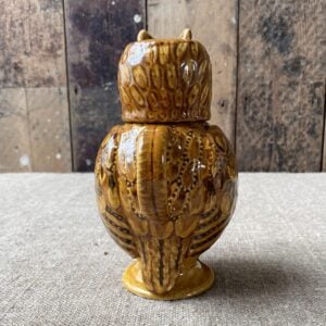 Carole Glover slipware glazed Owl Jug against a wooden background