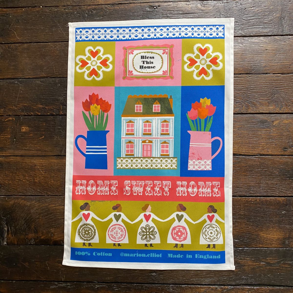 Illustrated Teatowel by Marion Elliot of a house, tulips and a dancing figure border