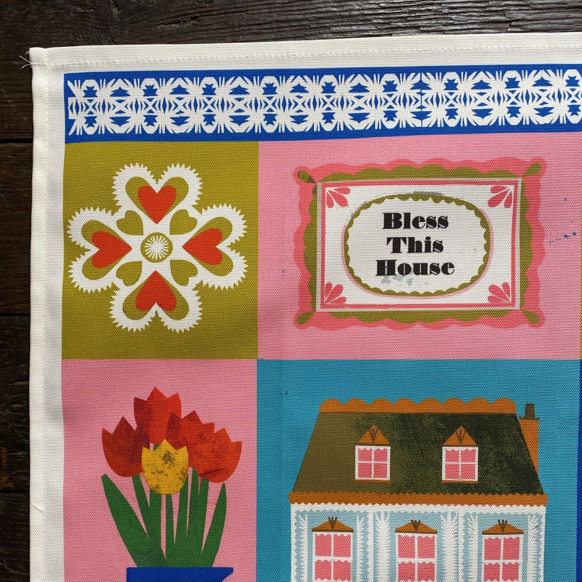 Illustrated Teatowel by Marion Elliot of a house, tulips and a dancing figure border