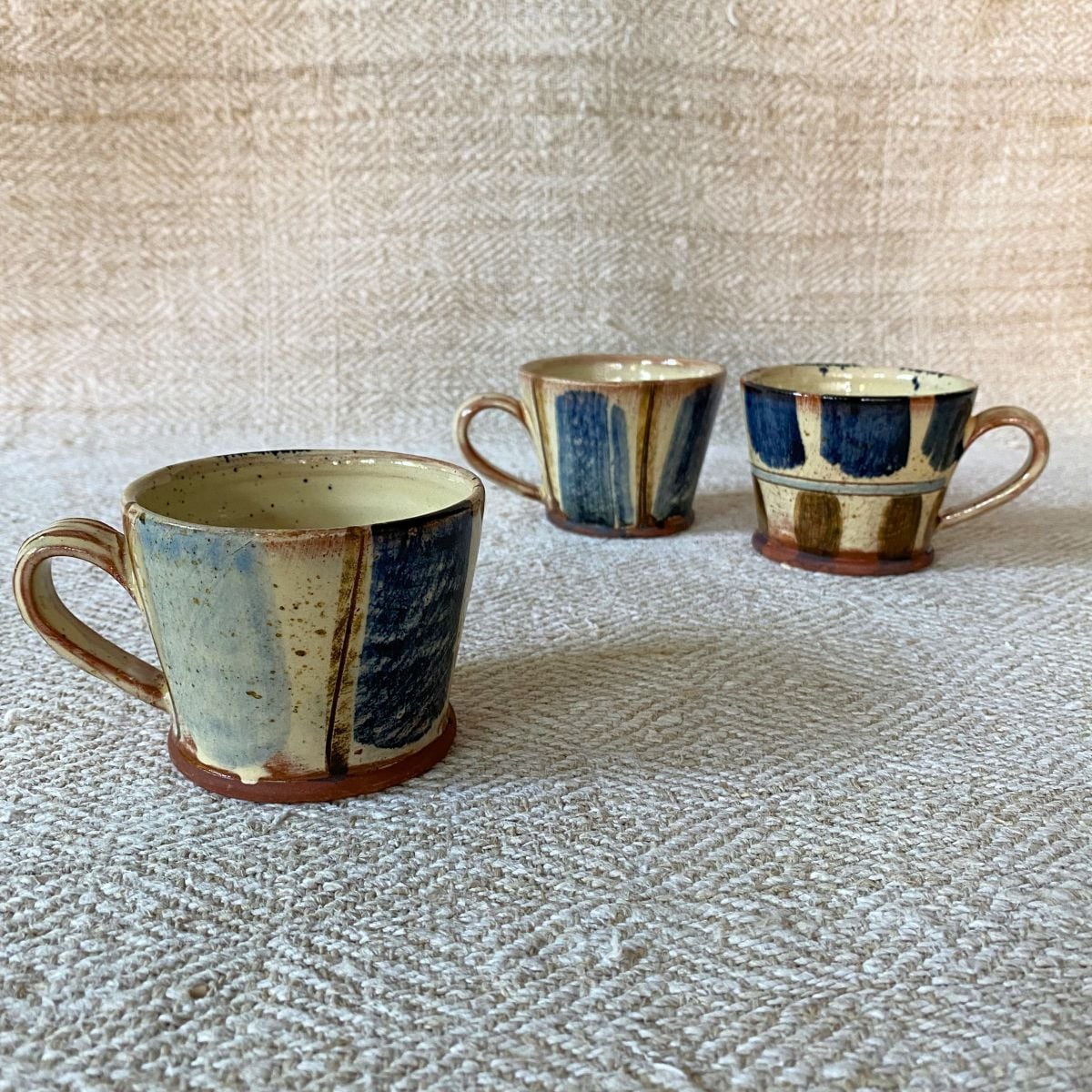 Jennifer Hall trio of slipware glazed espresso mugs on a cream textile background