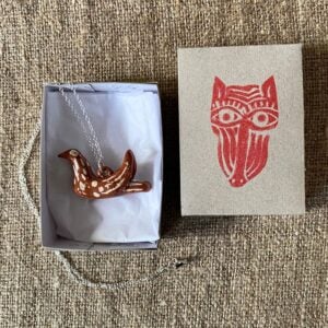 Emma Carlow pottery whistle necklace bird on a cloth background