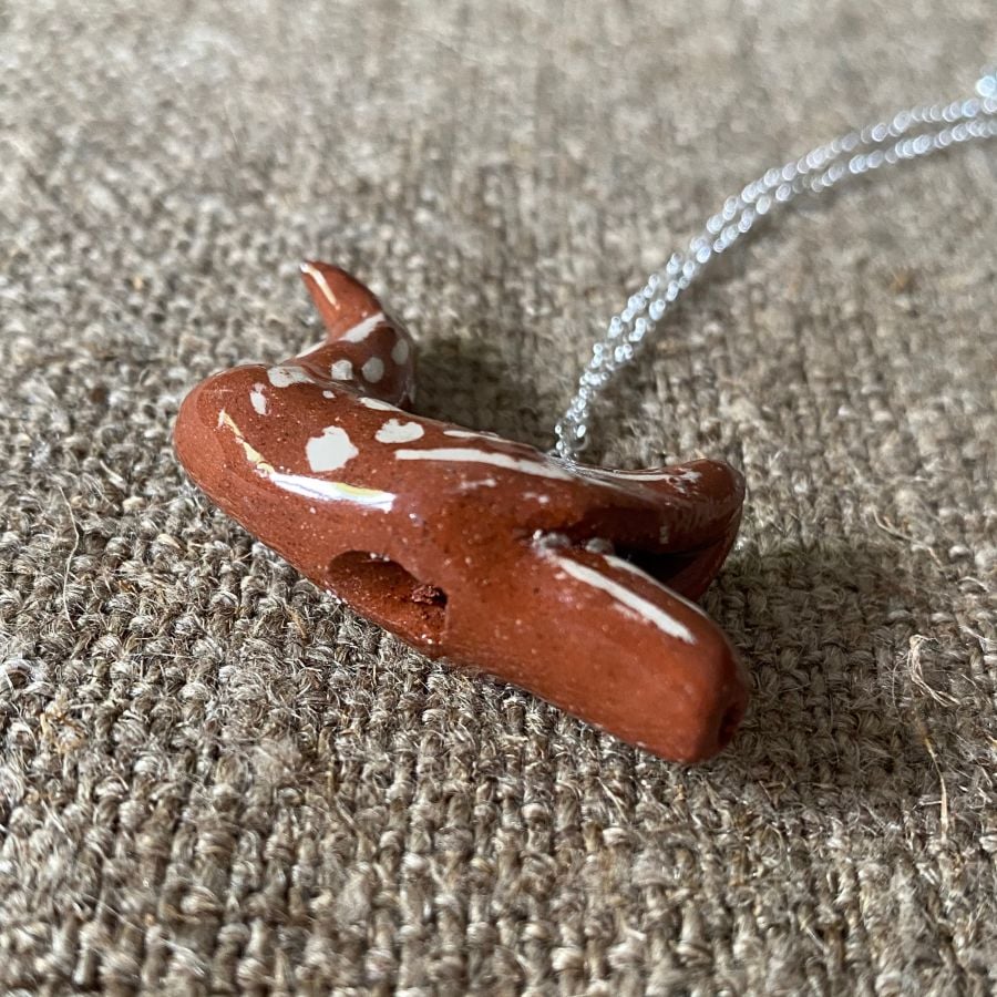 Emma Carlow pottery whistle necklace bird on a cloth background