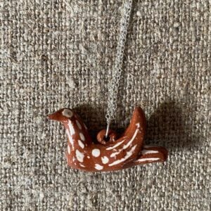 Emma Carlow pottery whistle necklace bird on a cloth background