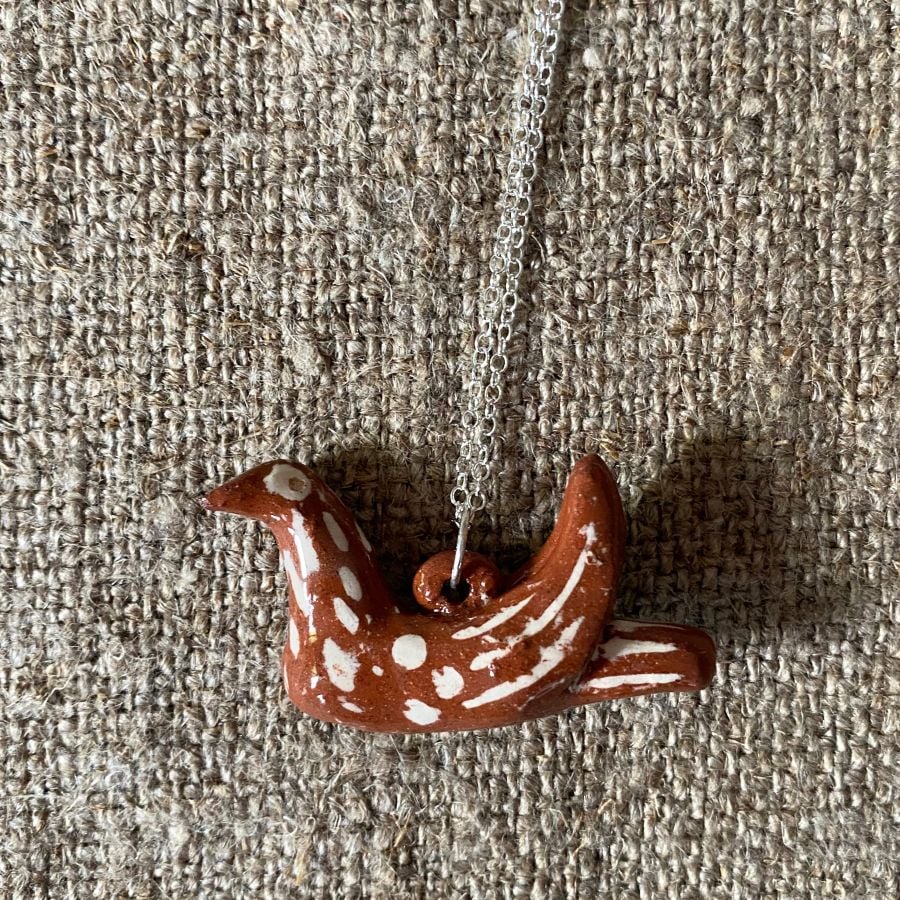 Emma Carlow pottery whistle necklace bird on a cloth background