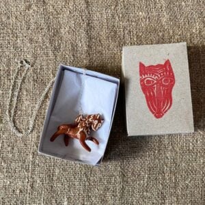 Emma Carlow pottery whistle necklace lion on a cloth background