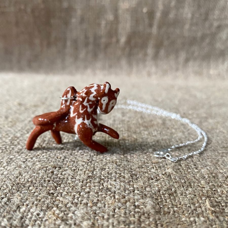 Emma Carlow pottery whistle necklace lion on a cloth background