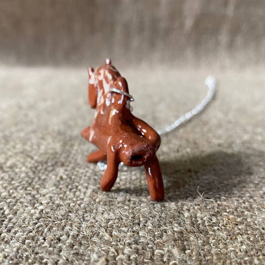Emma Carlow pottery whistle necklace lion on a cloth background