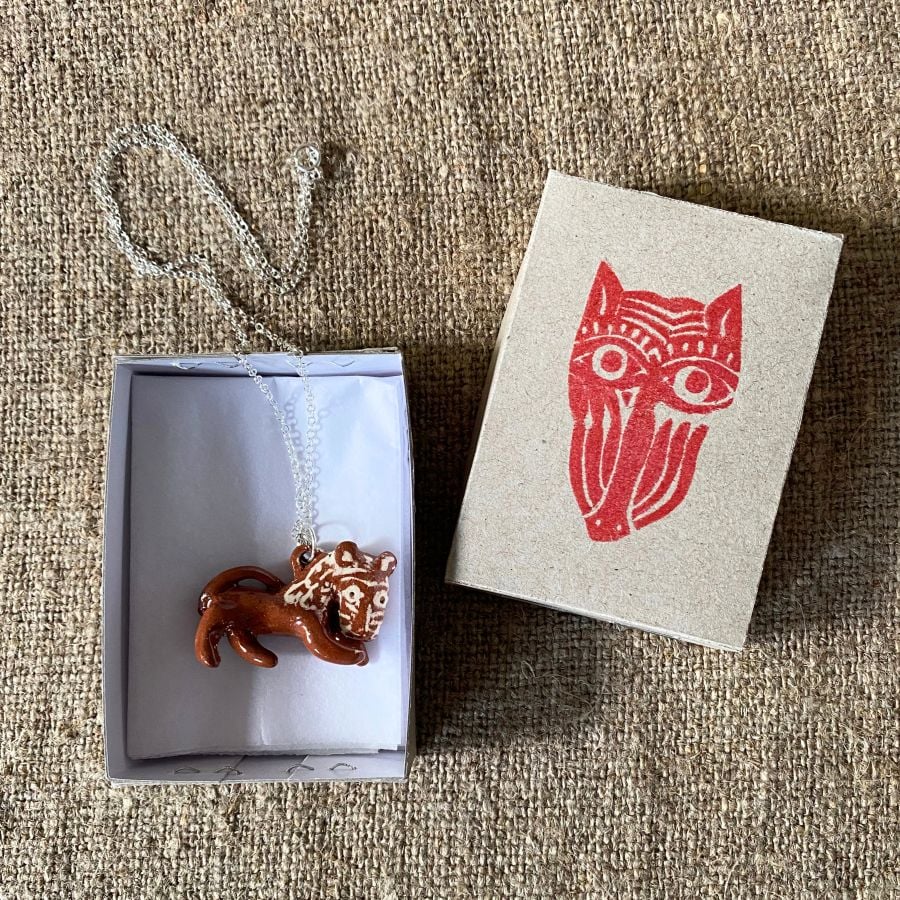 Emma Carlow pottery whistle necklace lion on a cloth background