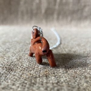 Emma Carlow pottery whistle necklace lion on a cloth background
