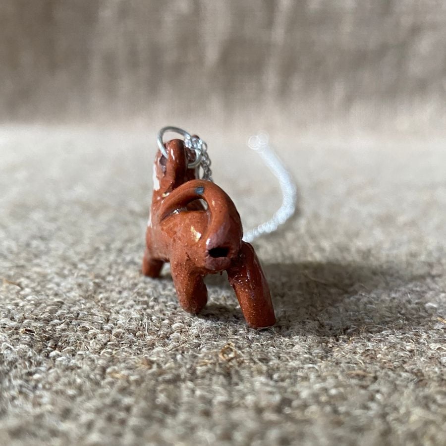 Emma Carlow pottery whistle necklace lion on a cloth background
