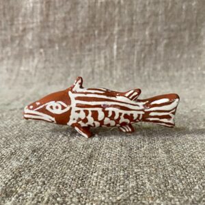 Emma Carlow pottery whistle in the shape of a FISH against a cloth backdrop