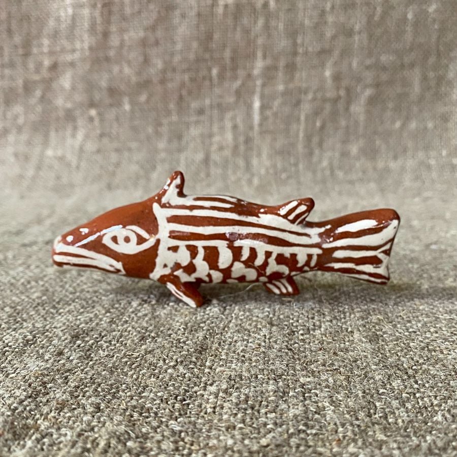 Emma Carlow pottery whistle in the shape of a FISH against a cloth backdrop