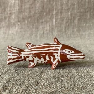Emma Carlow pottery whistle in the shape of a FISH against a cloth backdrop