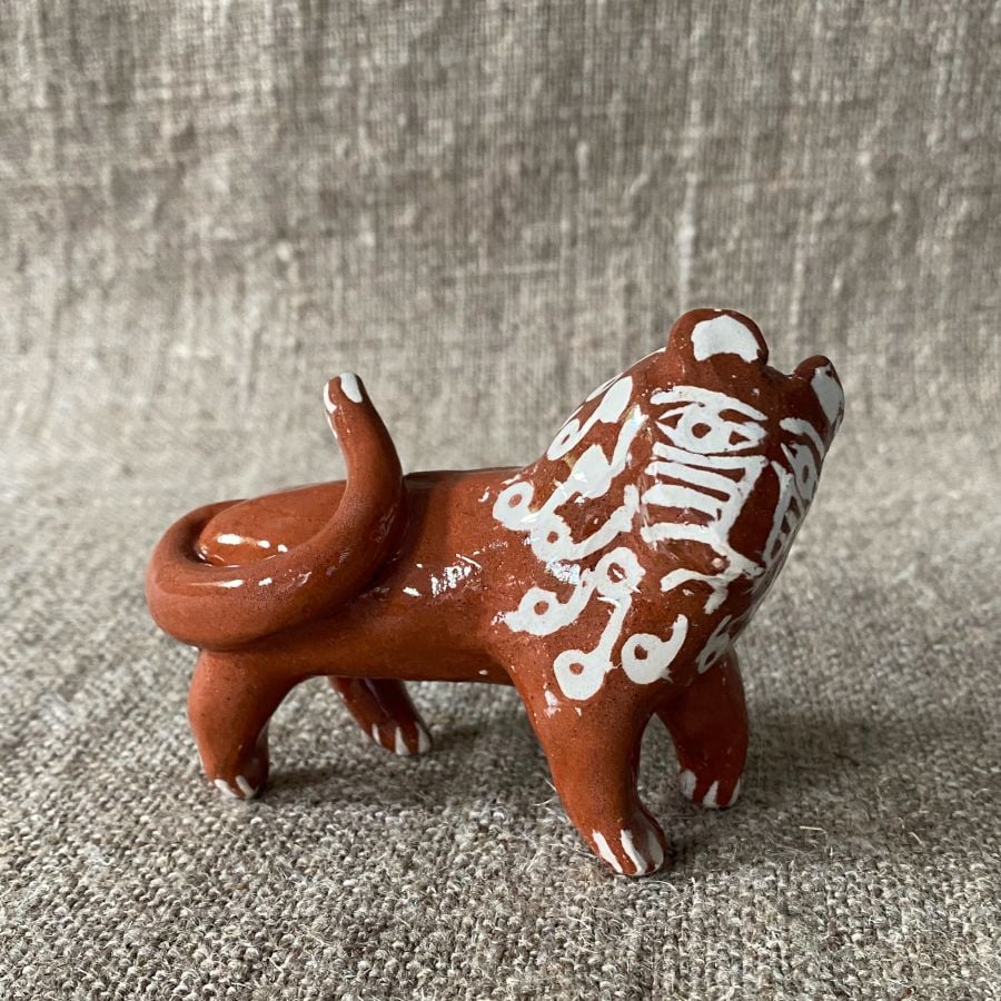 Emma Carlow pottery whistle in the shape of a Lion against a cloth backdrop