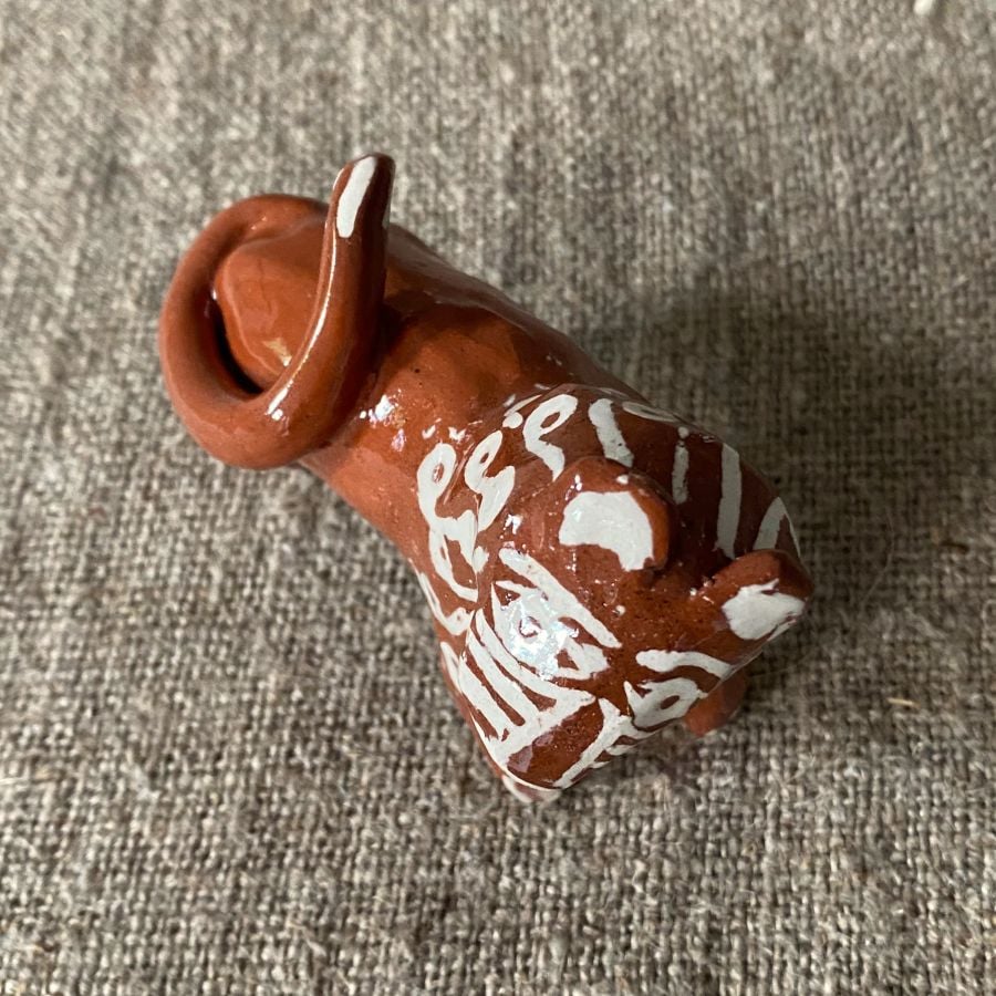 Emma Carlow pottery whistle in the shape of a Lion against a cloth backdrop